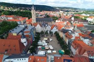 Markt mit Ständen, umrandet von Bäumen und alten Gebäuden.