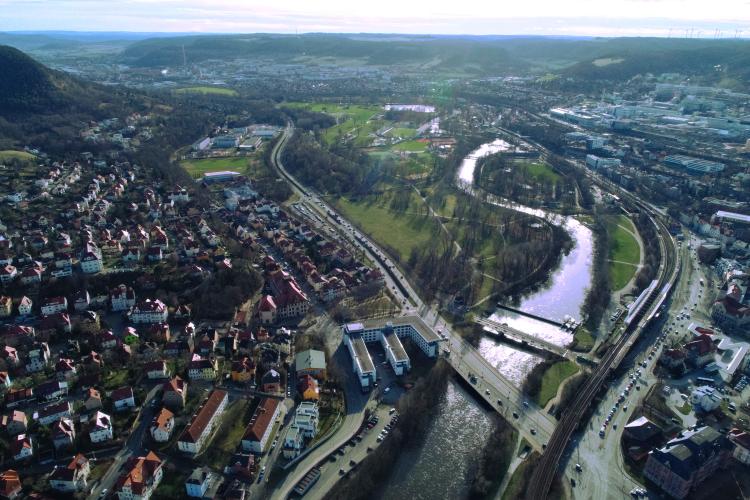 Schräges Luftbild mit Blick über ein Wohngebiet an der Saale. Im Hintergrund der Paradiespark, durch den sich die Saale schlängelt.