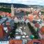 Markt mit Ständen, umrandet von Bäumen und alten Gebäuden.