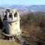 Steinerner runder Turm auf einem Gipfel; im Hintergrund Jena-Ost und das Stadtzentrum mit JenTower